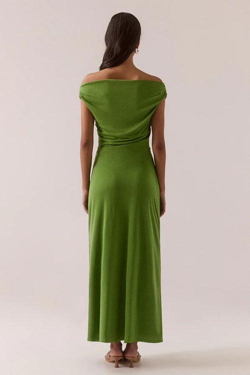 Woman wearing a green off-shoulder dress against a white background