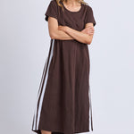 Woman wearing a brown dress with white stripes on a plain background