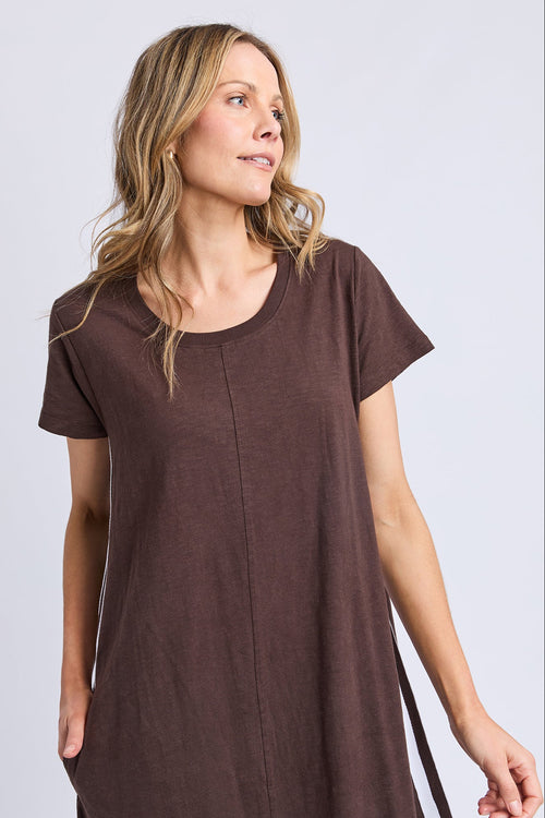 Woman wearing a brown dress against a plain background