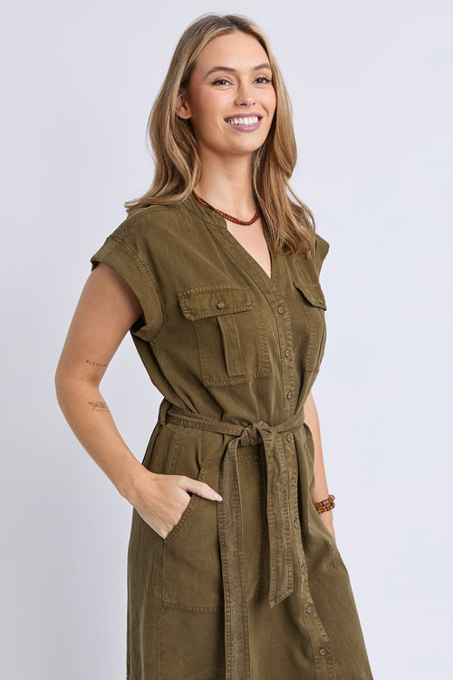 Woman wearing a green dress with a belt against a light gray background