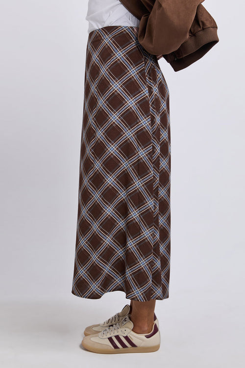 Person wearing a brown plaid skirt with a white background