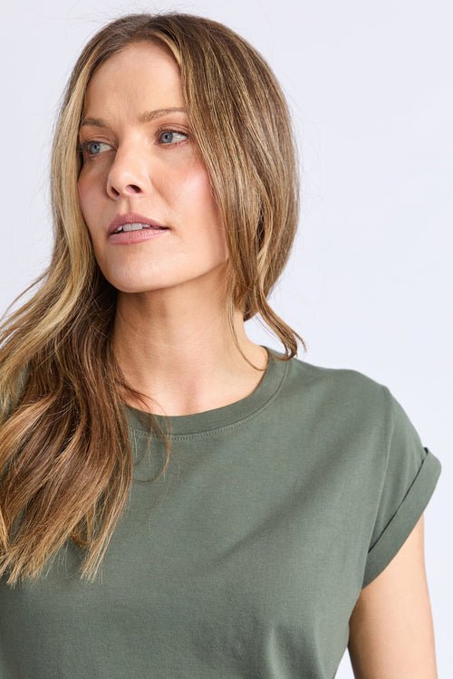 Woman wearing a green scoop neck tee and dark blue jeans