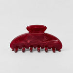 A glossy dark red hair claw clip with a marbled tortoiseshell-like finish, photographed on a clean light gray background.