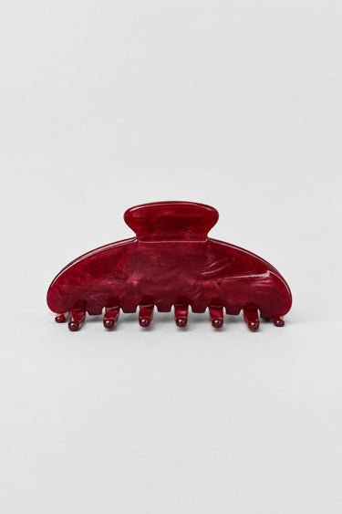 A glossy dark red hair claw clip with a marbled tortoiseshell-like finish, photographed on a clean light gray background.
