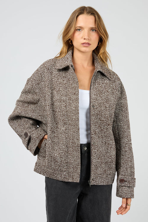 Woman wearing a brown patterned jacket on a light gray background