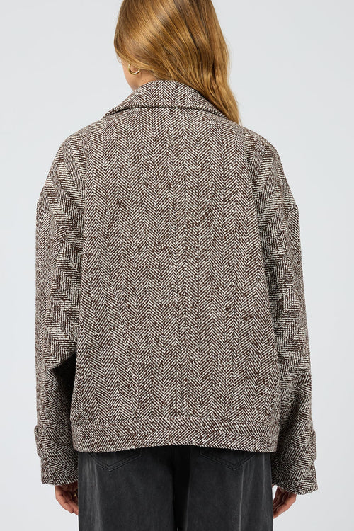 Person wearing a textured brown jacket on a plain background