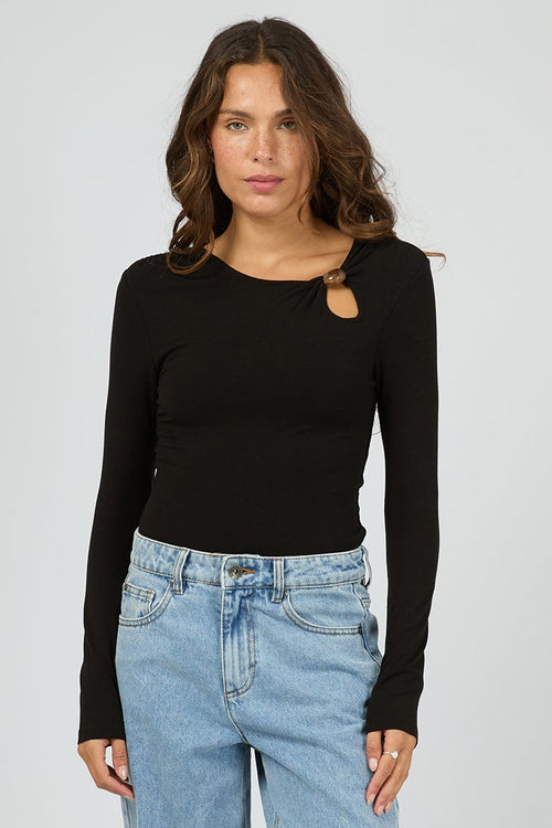 Woman wearing a black long-sleeve top and light blue jeans on a white background
