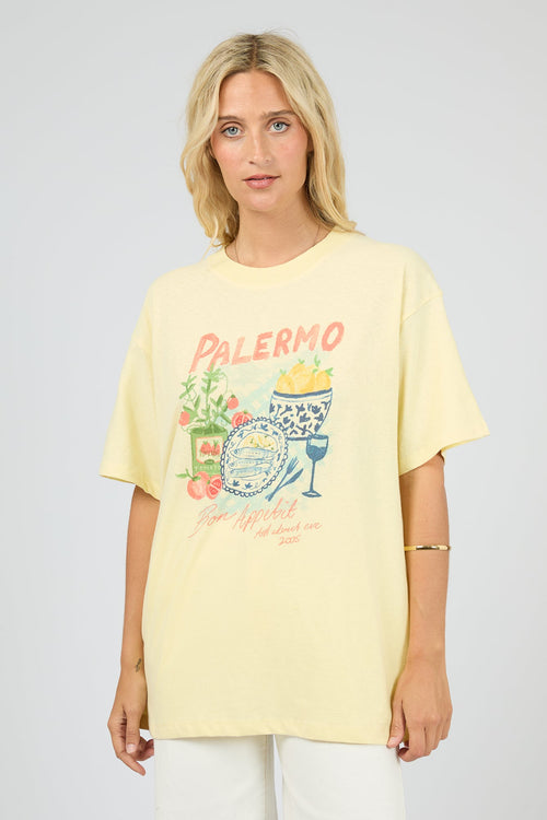 Woman wearing a yellow t-shirt with a graphic design on a plain background