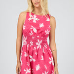 Woman wearing a pink dress with white floral patterns on a gray background