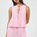 Woman wearing a pink and white striped sleeveless top and pants on a light gray background