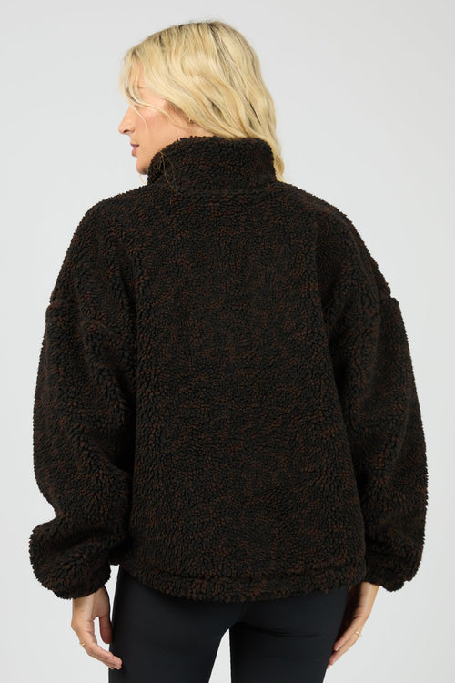 Person wearing a dark brown fleece jacket on a plain background