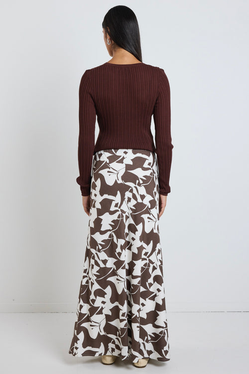 Model wears brown pattern maxi skirt with a tie waist and a long sleeve brown top. 