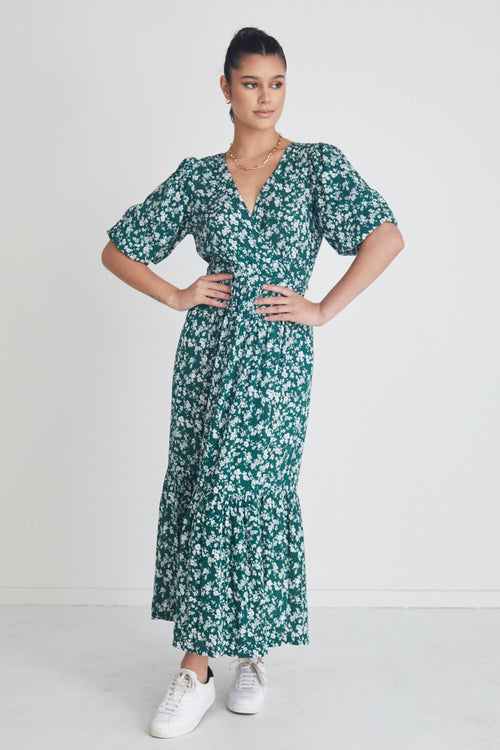 model posing in green floral maxi dress and white sneakers