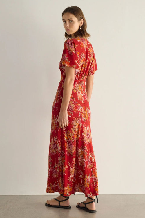 Woman wearing a red floral dress on a plain background