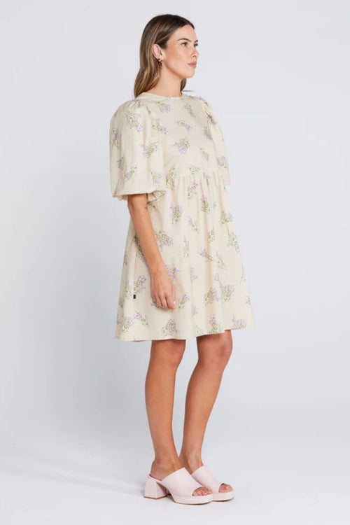 Woman wearing a cream floral mini dress with puff sleeves