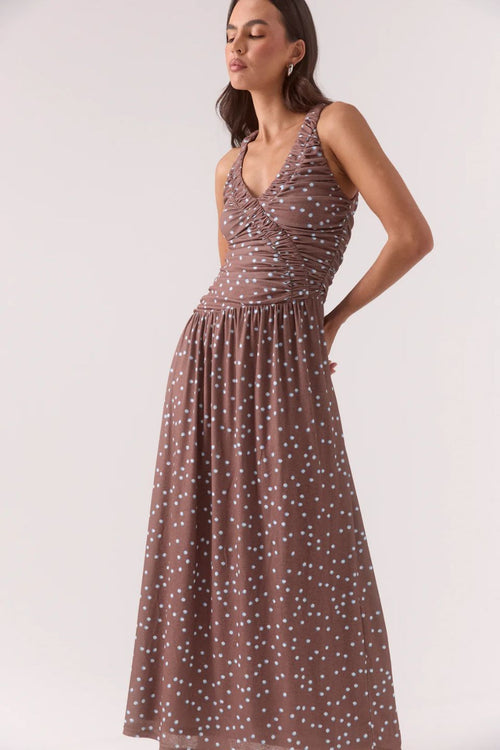 Woman wearing a brown and blue polka dot ruched maxi dress