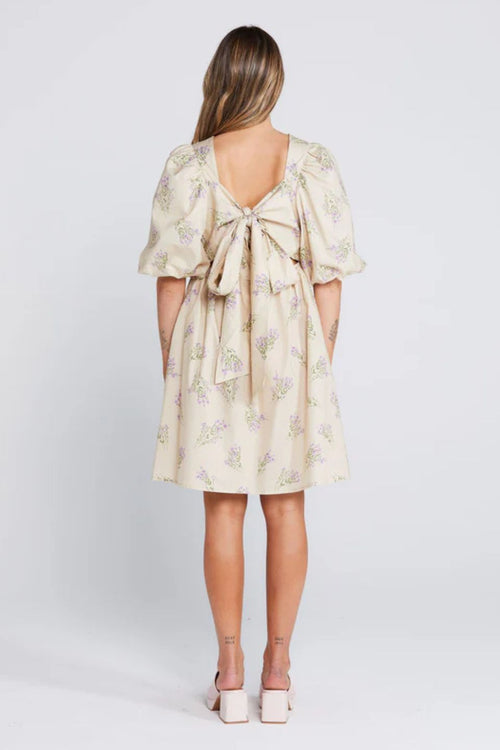 Woman wearing a cream floral mini dress with puff sleeves