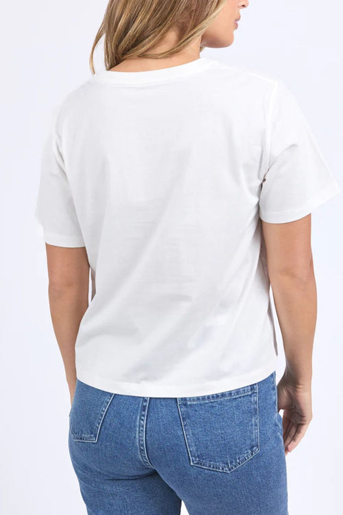 Woman wears a white apple print shirt and blue denim