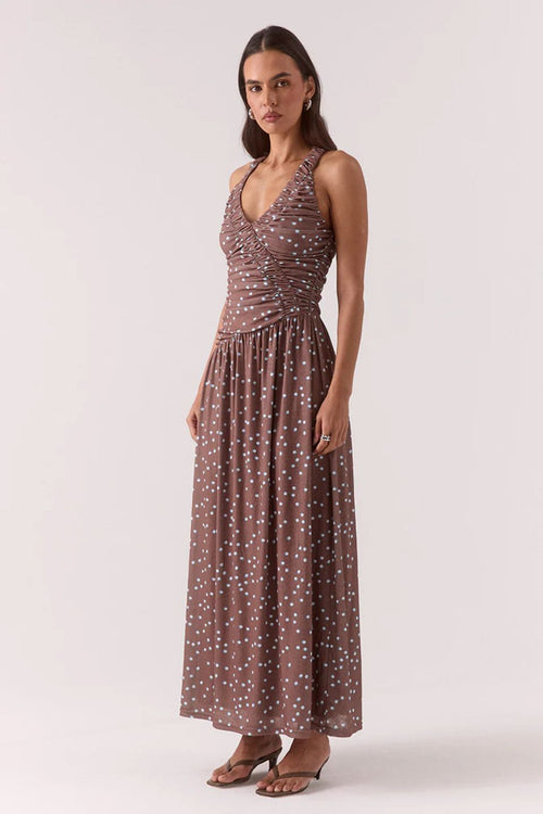 Woman wearing a brown and blue polka dot ruched maxi dress