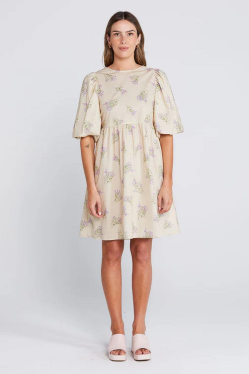 Woman wearing a cream floral mini dress with puff sleeves