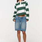 Woman wearing a green and white striped shirt with denim shorts on a white background