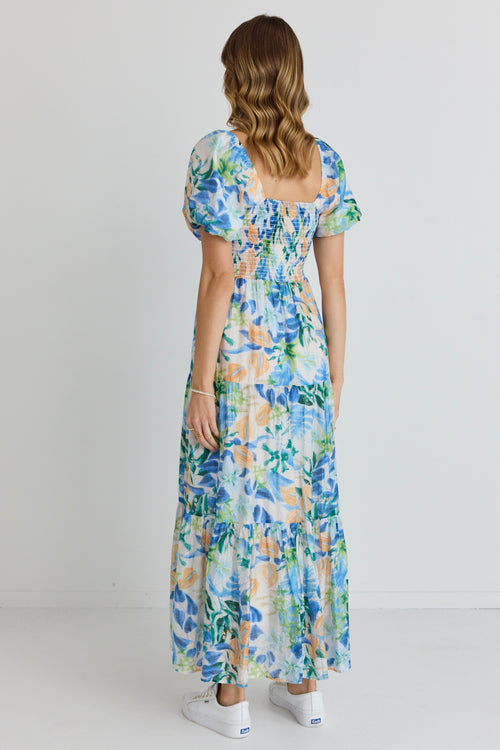 model is outside and wears and blue and orange floral maxi dress with sandals