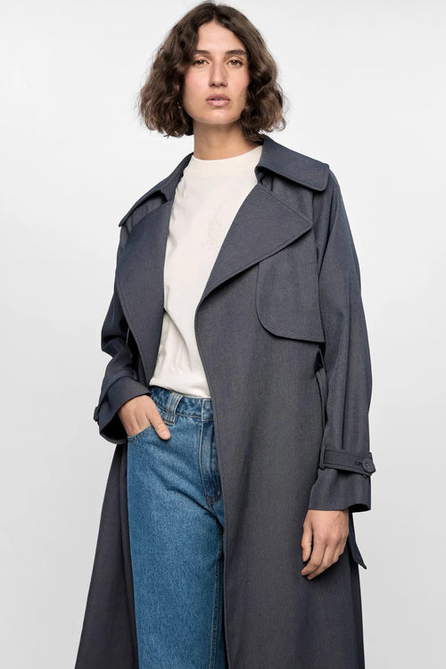 Model wears a grey trench coat with large collar 