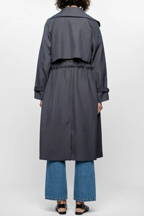 Model wears a grey trench coat with large collar 