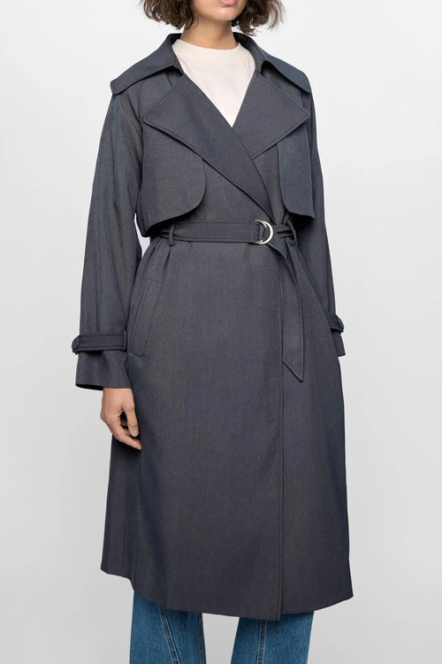 Model wears a grey trench coat with large collar 