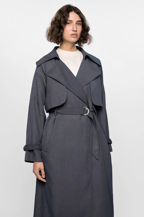 Model wears a grey trench coat with large collar 
