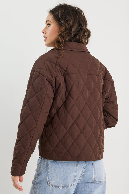 Person wearing a brown quilted jacket on a white background