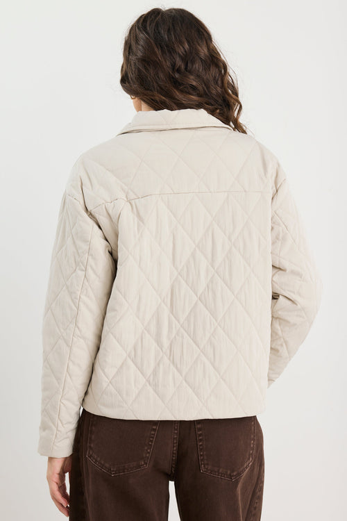 Person wearing a beige quilted jacket on a white background
col_pattern