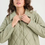 Woman wearing a green quilted jacket on a white background