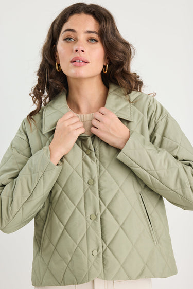 Woman wearing a green quilted jacket on a white background