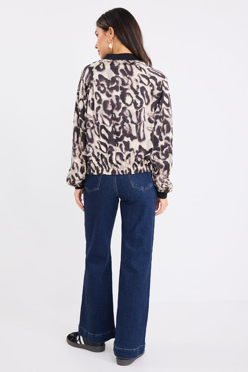 model wears a leopard bomber jacket with dark blue jeans