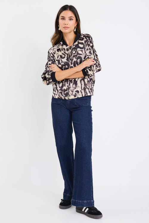 model wears a leopard bomber jacket with dark blue jeans