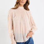 Woman wearing a beige blouse and blue jeans on a white background