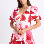 Woman wearing a pink and red floral dress on a white background