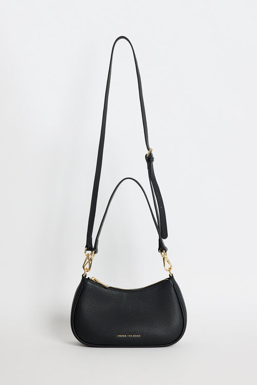 A black pebbled leather crescent-shaped shoulder bag with gold-tone hardware and a long adjustable shoulder strap, shown against a plain light gray background.