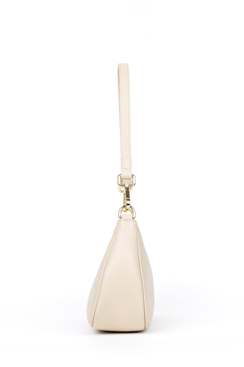 A cream-colored leather shoulder bag with a matching wristlet strap and gold-tone hardware, shown from a side profile view on a white background.