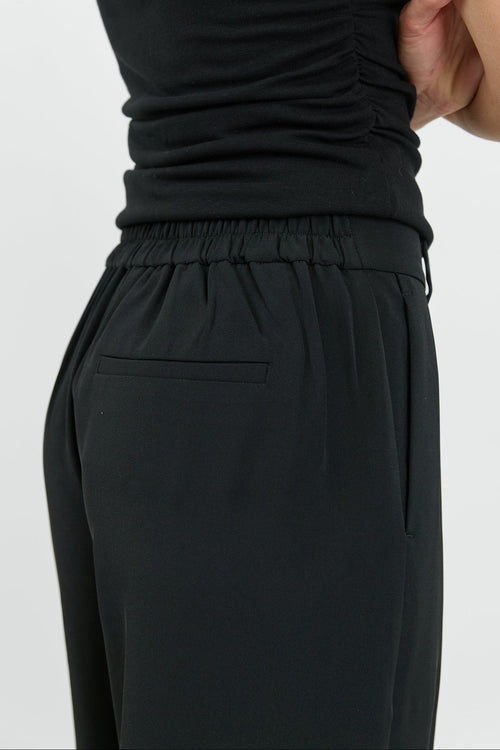 Person wearing a black sleeveless top and black pants on a white background