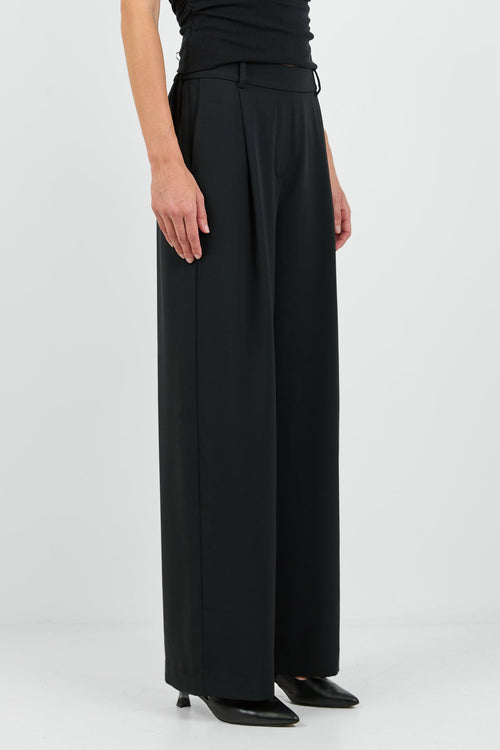 Person wearing a black sleeveless top and wide-leg pants on a white background