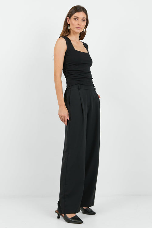 Woman wearing a black sleeveless top and wide-leg pants on a white background