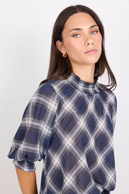 Woman wearing a blue and white plaid shirt against a plain background