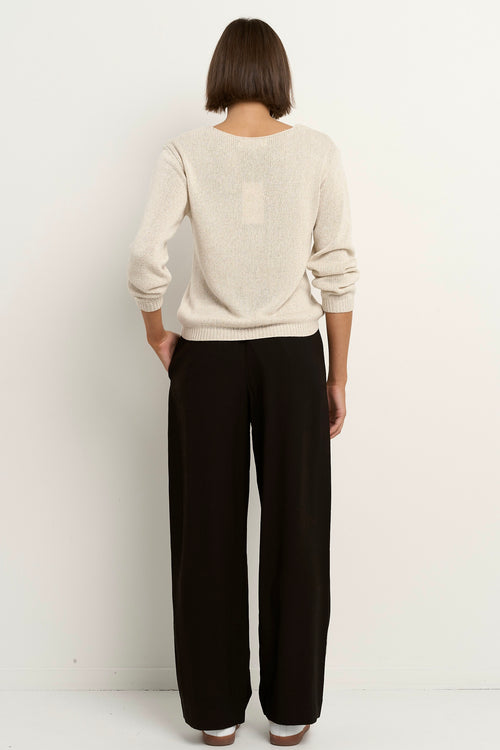 Woman wearing a natural beige V-neck jumper with black drawstring pants featuring white side stripes.