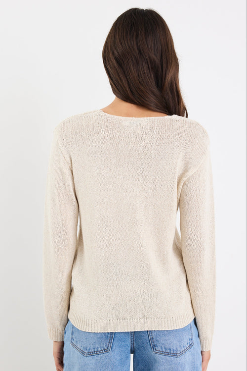 Person wearing a beige sweater and blue jeans on a white background