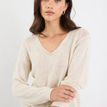 Woman wearing a beige sweater against a white background