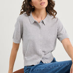 Woman wearing a grey knit and blue jeans on a white background