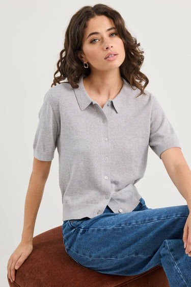 Woman wearing a grey knit and blue jeans on a white background