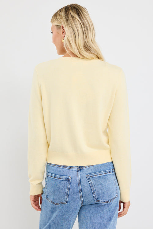 model wears a yellow cardigan with light blue jeans